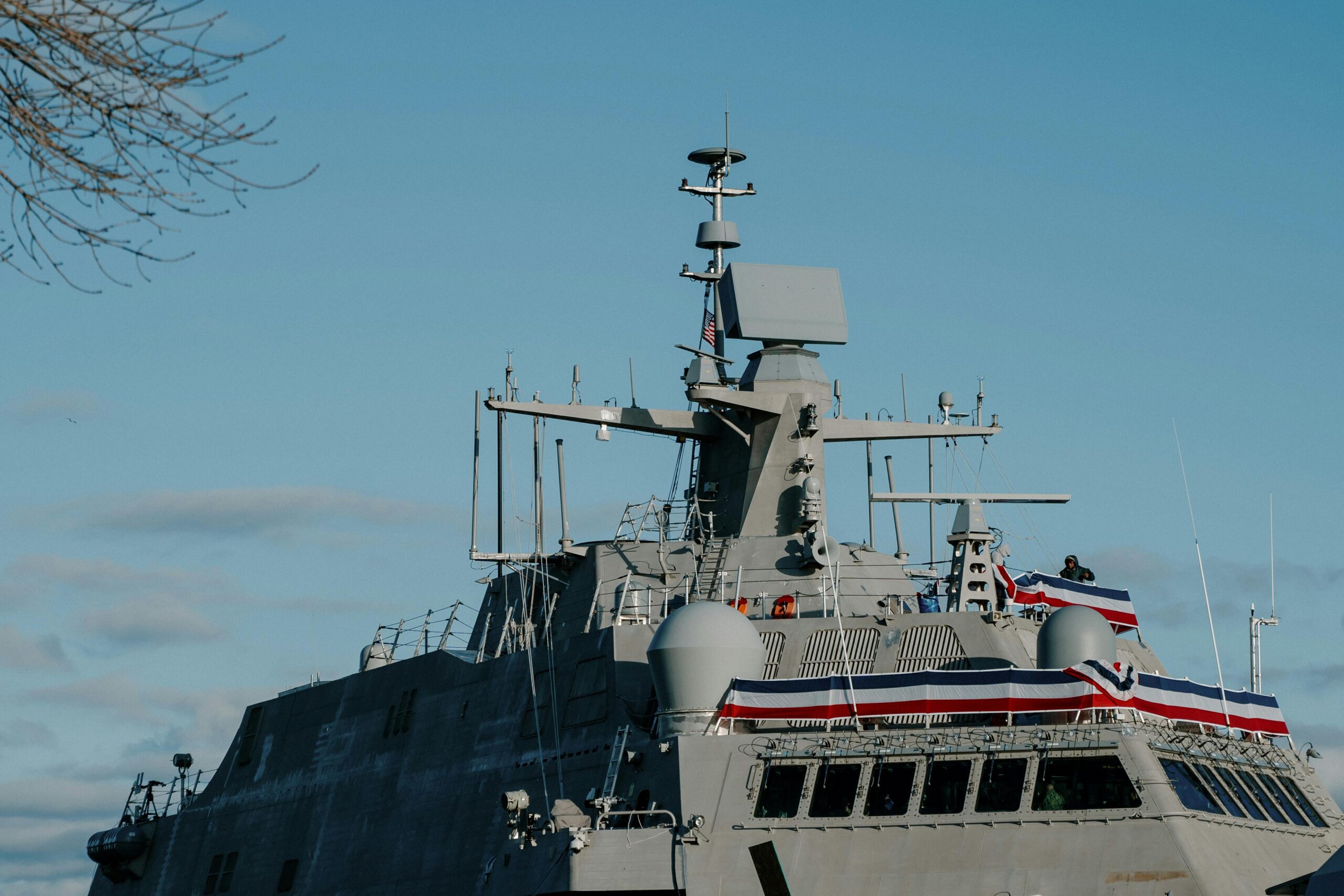 a modern warship adorned with flags, docked in milwaukee harbor.
