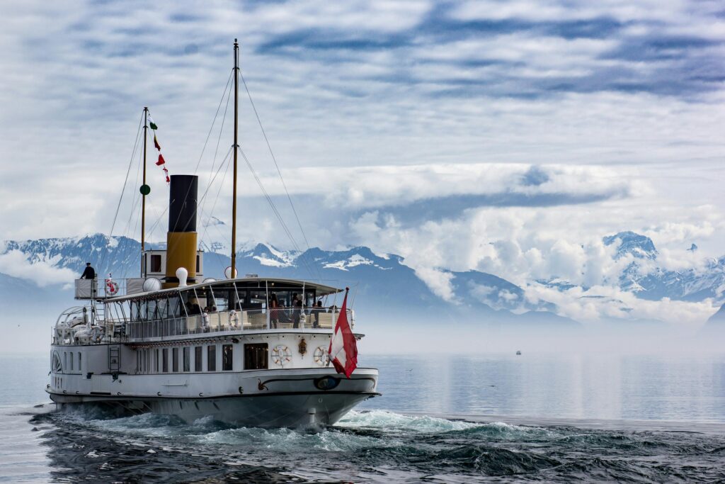 a luxury cruise ship sails on a misty lake with a snowy mountain backdrop.