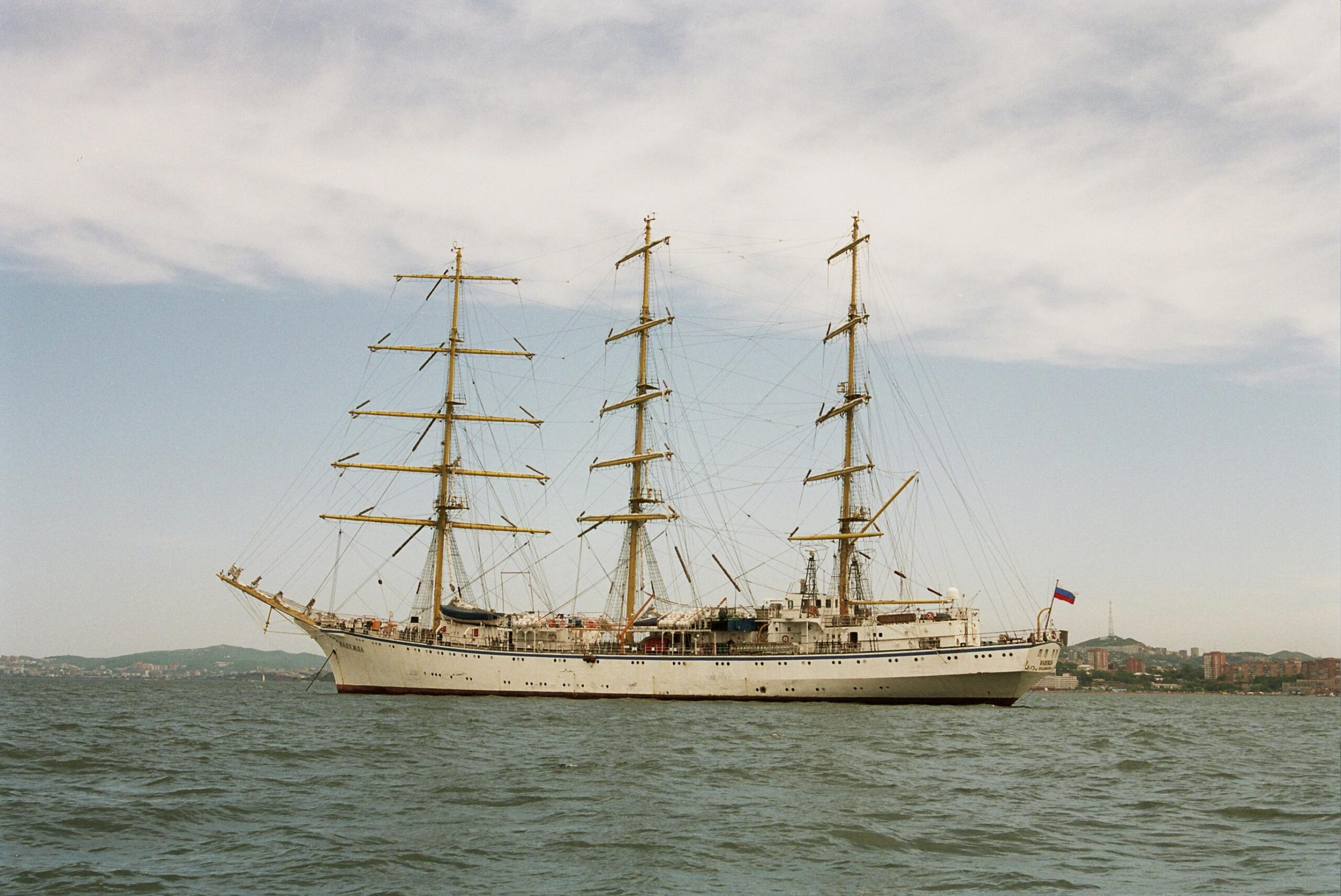 a grand sailing ship with multiple masts cruising on the ocean under a clear sky.