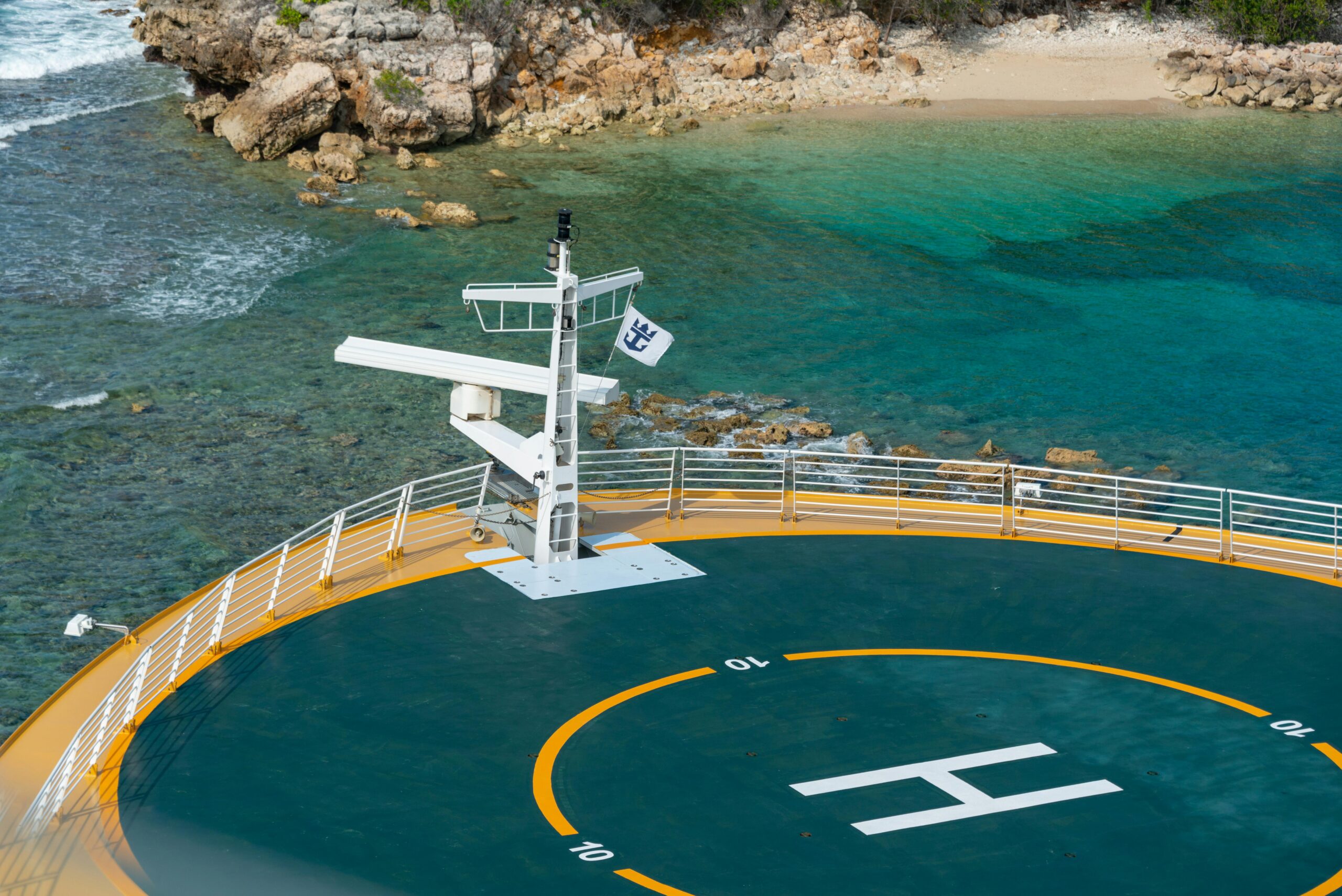 aerial view of a helipad on a ship with a stunning coastal backdrop.