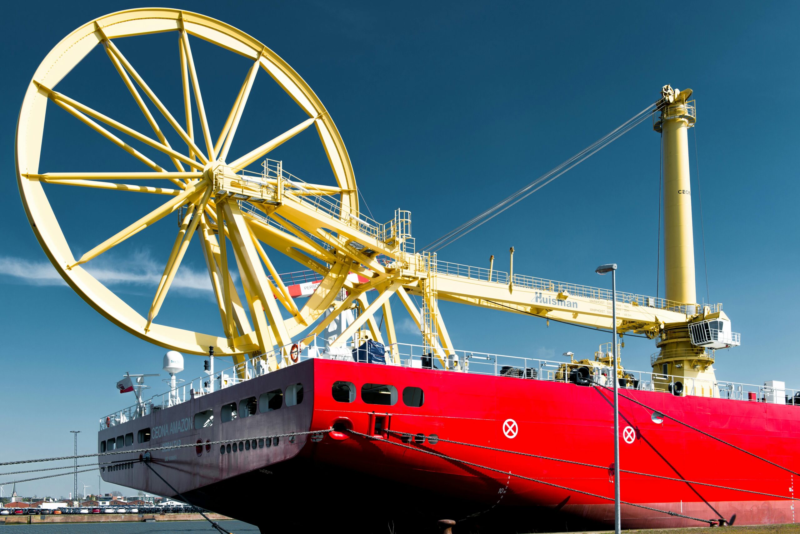 a red industrial cargo ship docked in bremerhaven harbor under a clear blue sky.