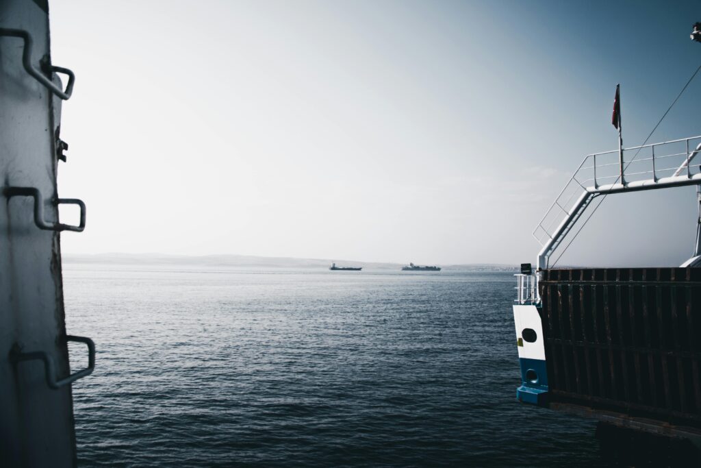 a tranquil ocean view from a ship deck under a clear sky, featuring distant vessels.