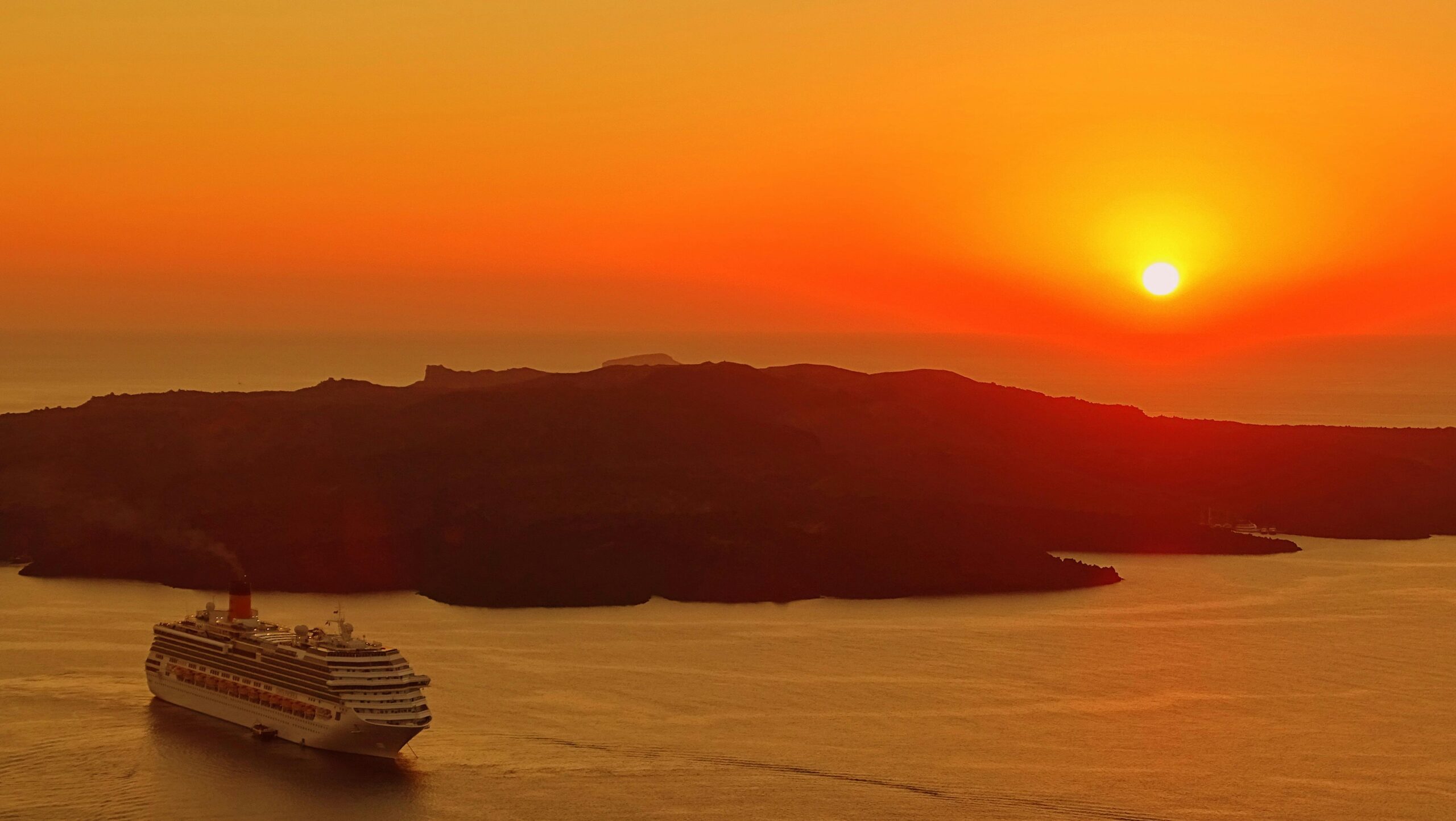 captivating sunset over santorini with a cruise ship navigating the calm sea.