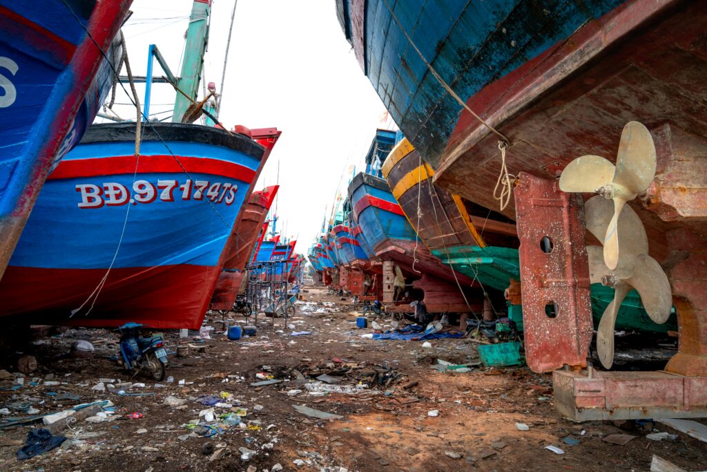 vibrant fishing boats lined up at a rustic shipyard, showcasing maritime industry and craftsmanship.