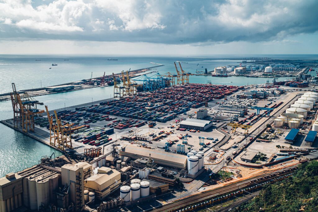 an elevated view of barcelona's bustling port with cranes and shipping containers.
