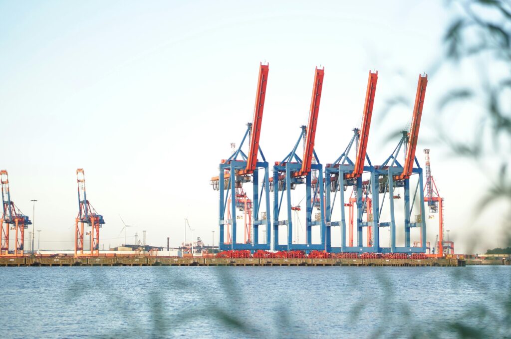 vibrant shipping cranes lined up at an industrial port on a clear day by the waterfront.