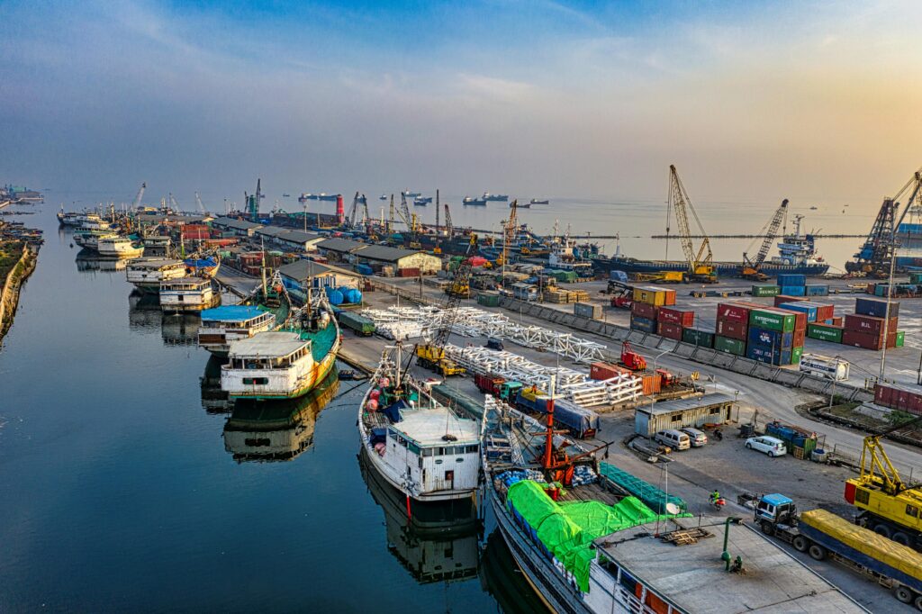 vibrant aerial shot of an industrial port with docked ships, cranes, and containers at dusk.