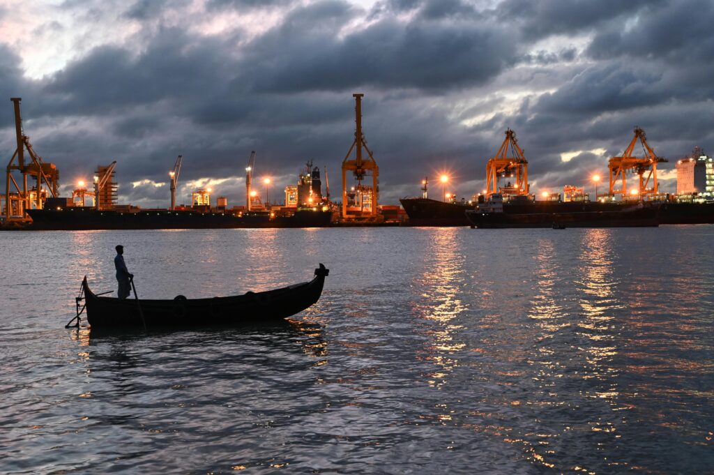 a fisherman on a boat during twilight at the industrial chittagong port, bangladesh.