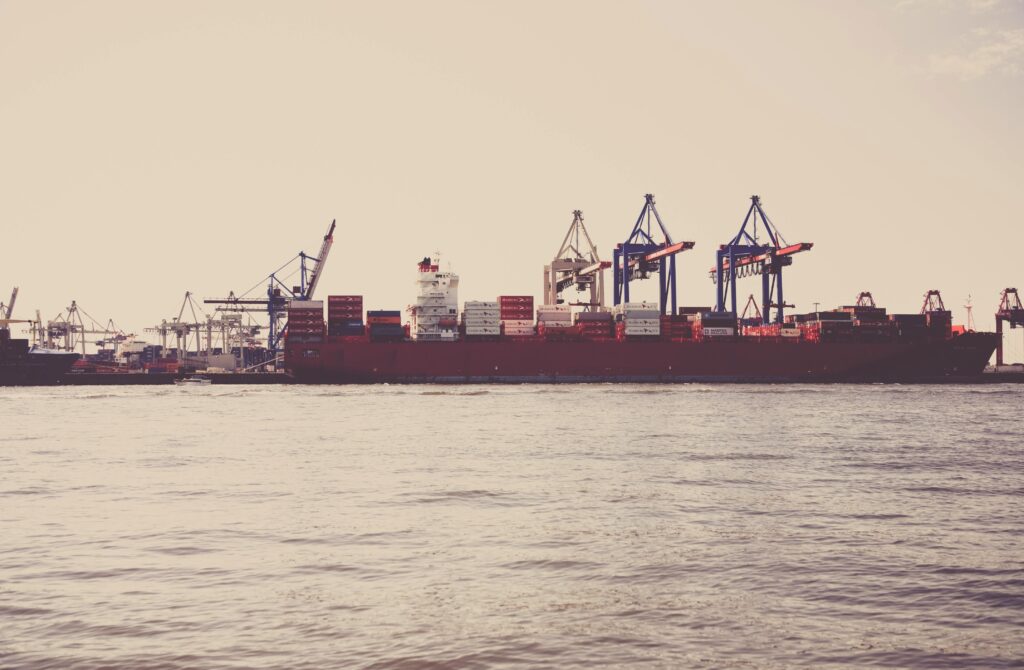 a cargo ship loaded with containers docked at a seaport under clear skies.