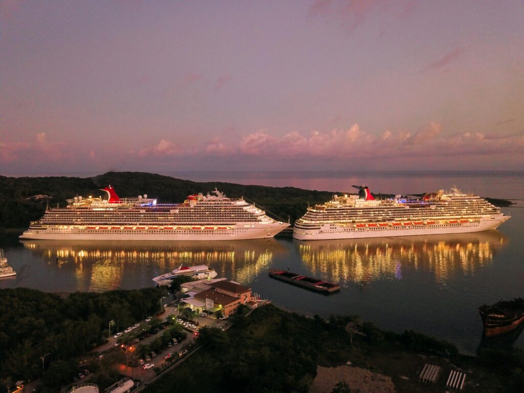 two illuminated cruise ships docked at coxen hole, honduras during twilight.