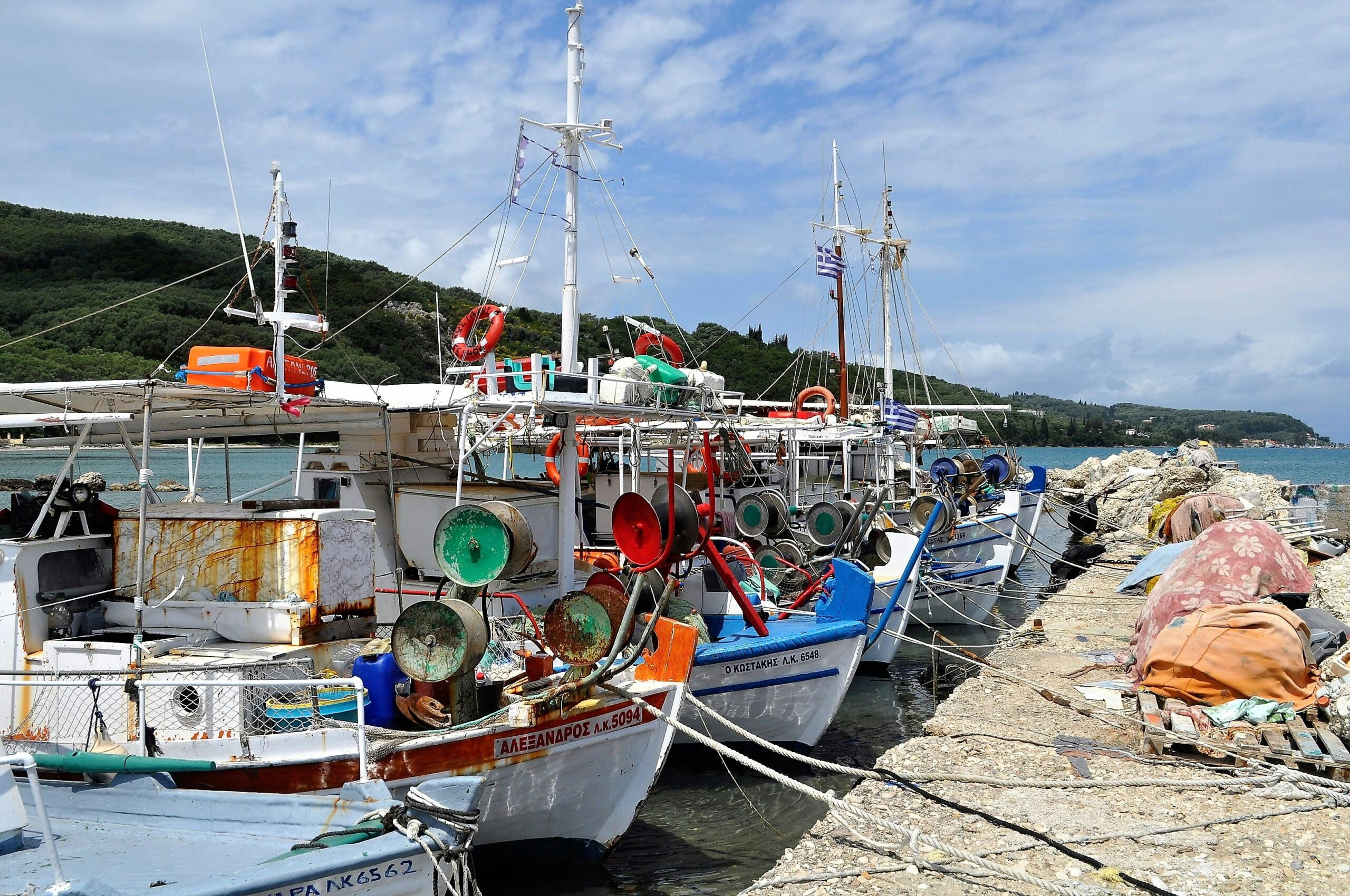 fishing boats moored at a picturesque harbor with nets and equipment, under a bright sky.