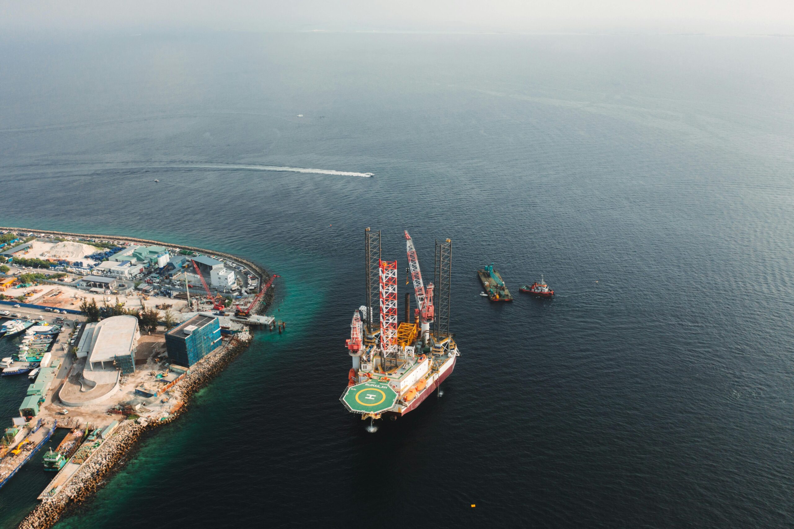 stunning aerial view of an offshore oil production platform with nearby ships and coastline.