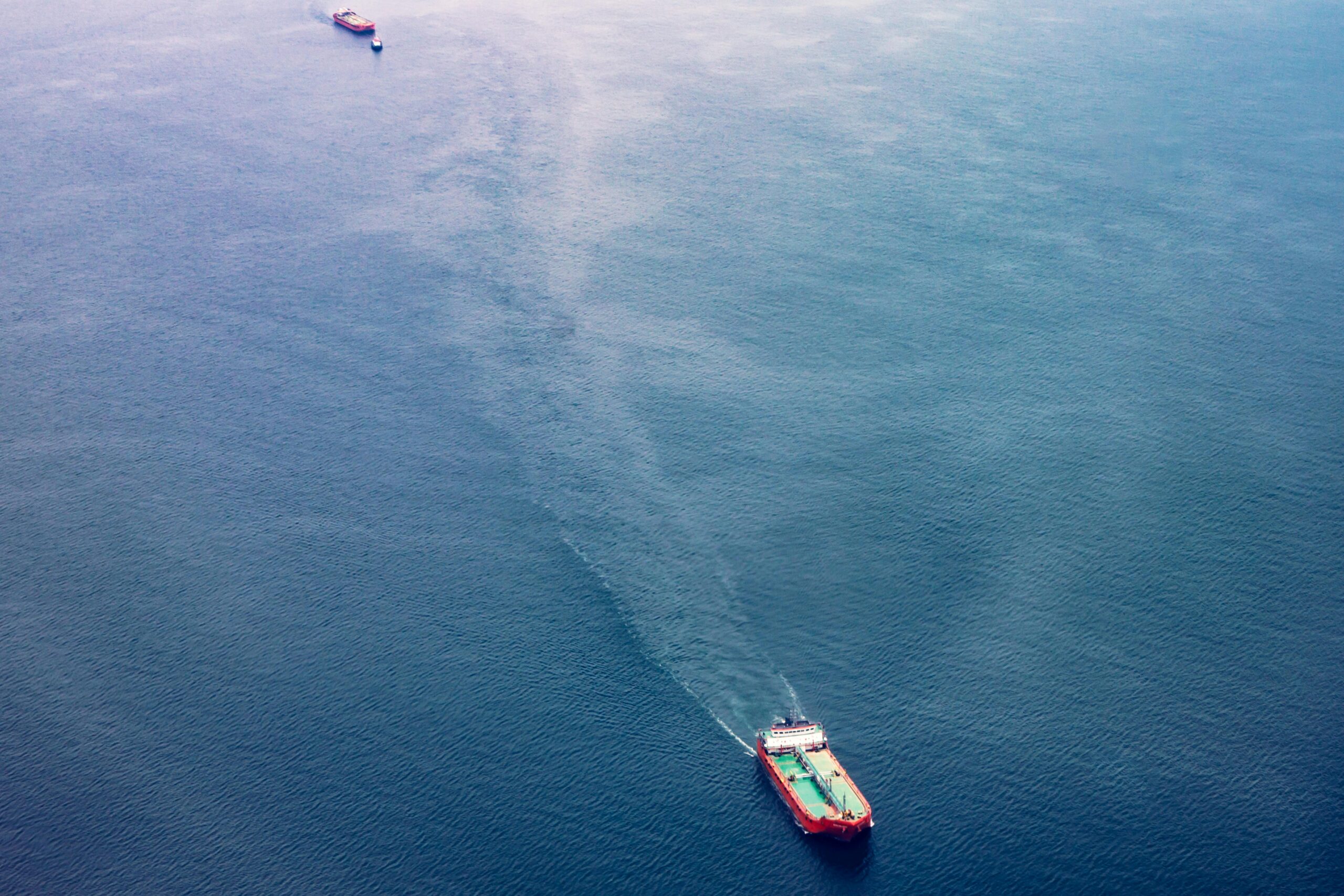 two cargo ships navigate the vast blue ocean, showcasing maritime transport.